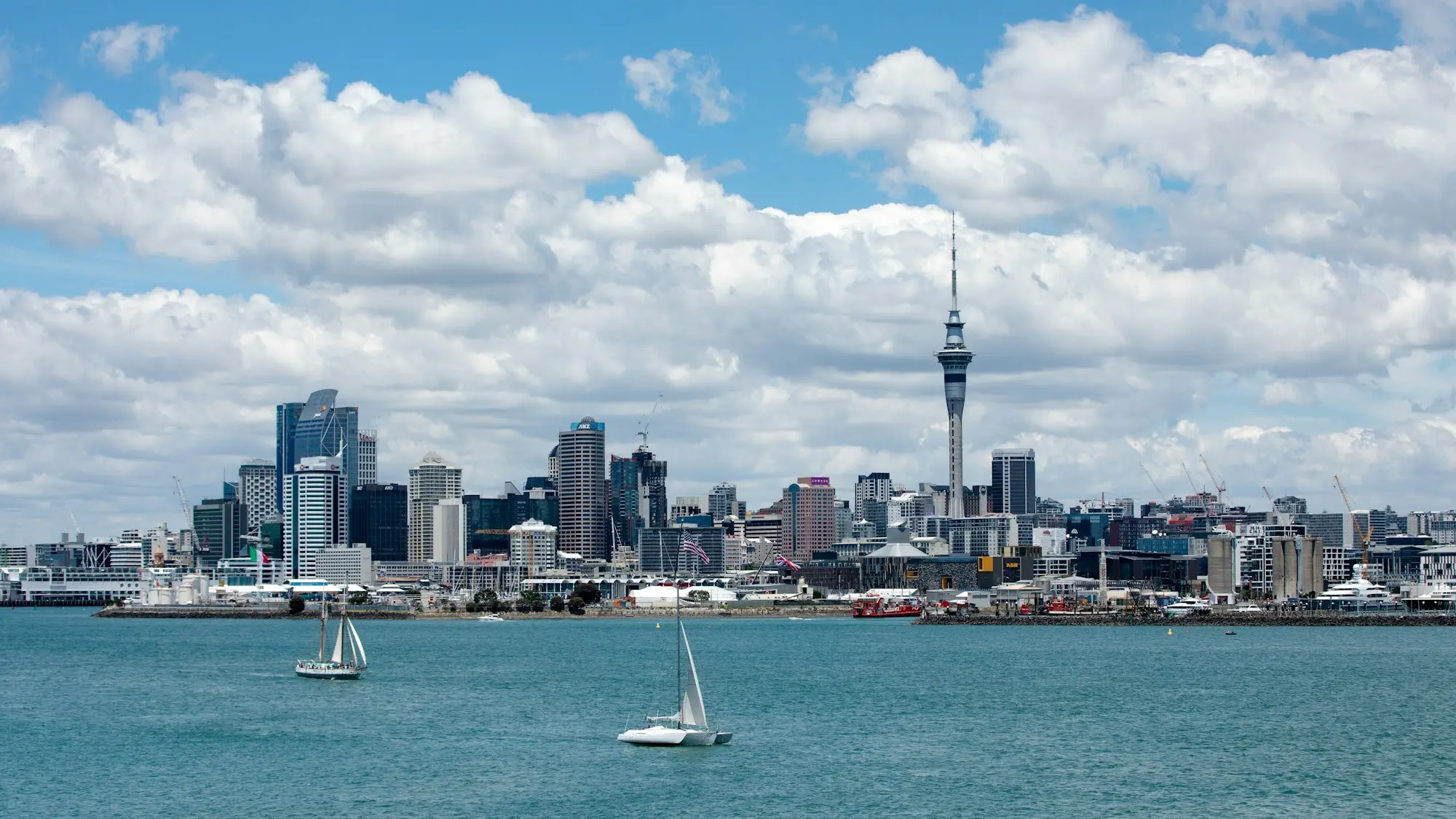 Sailboat on the Waitematā Harbour in front of Auckland city buildings on a clear day