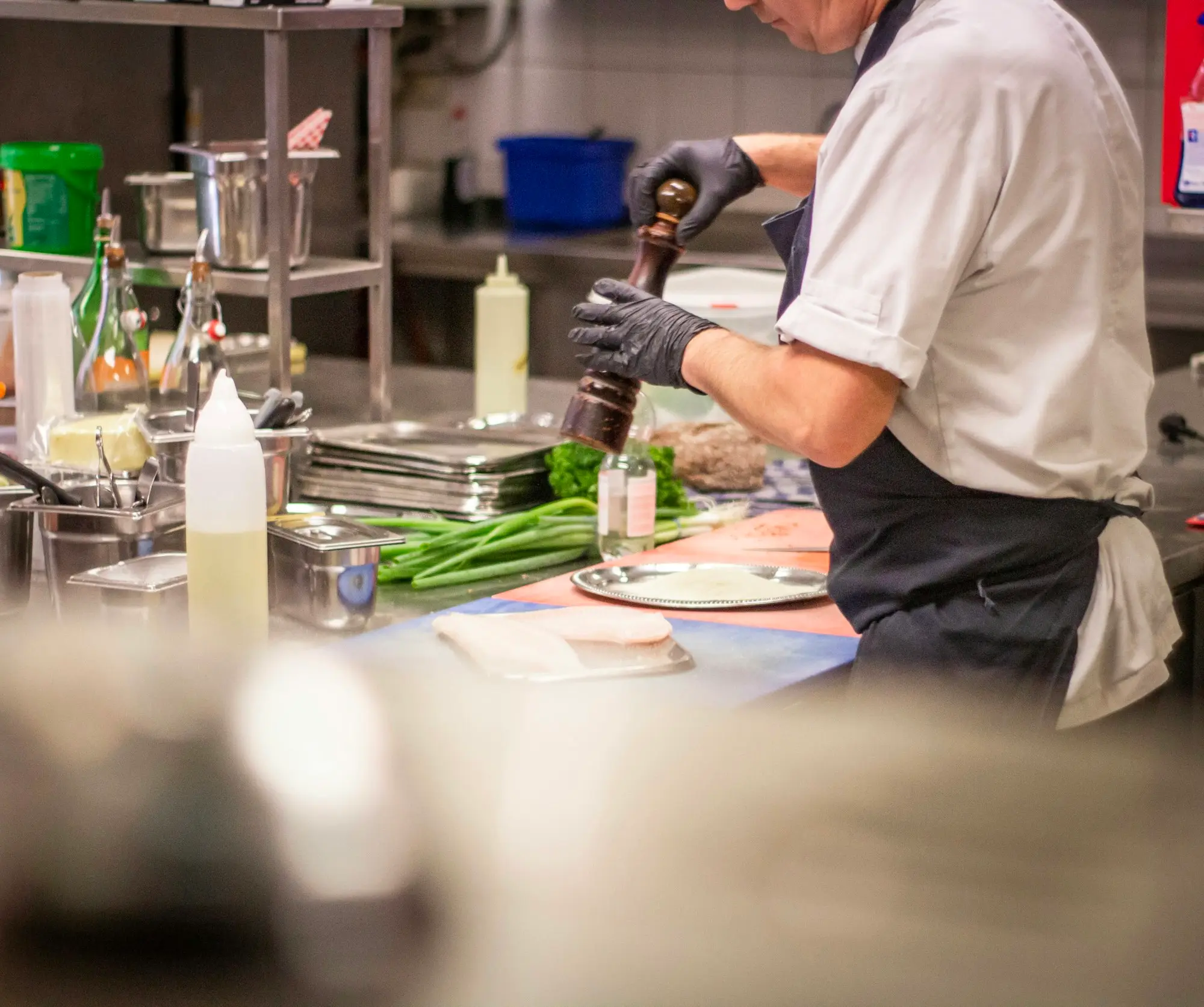 Chef adding herbs to a plated dish in a restaurant kitchen